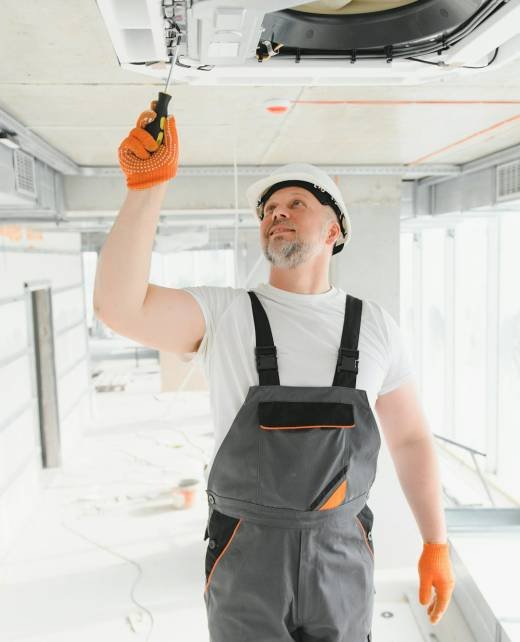 Worker repairing ceiling air conditioning unit Worker repairing ceiling air conditioning unit